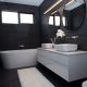 Black tiled bathroom with a bath tube and two sinks
