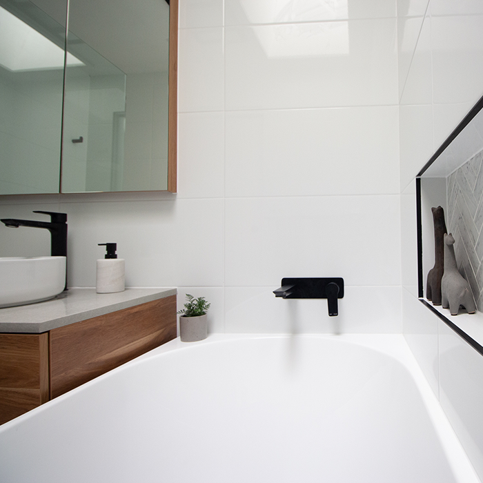 White tiled bathroom with bathtub and black fixtures