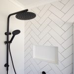 White tile bathroom with black shower head