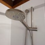 Steel shower head in white tile bathroom