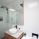 White tiled bathroom with black faucets and handles.