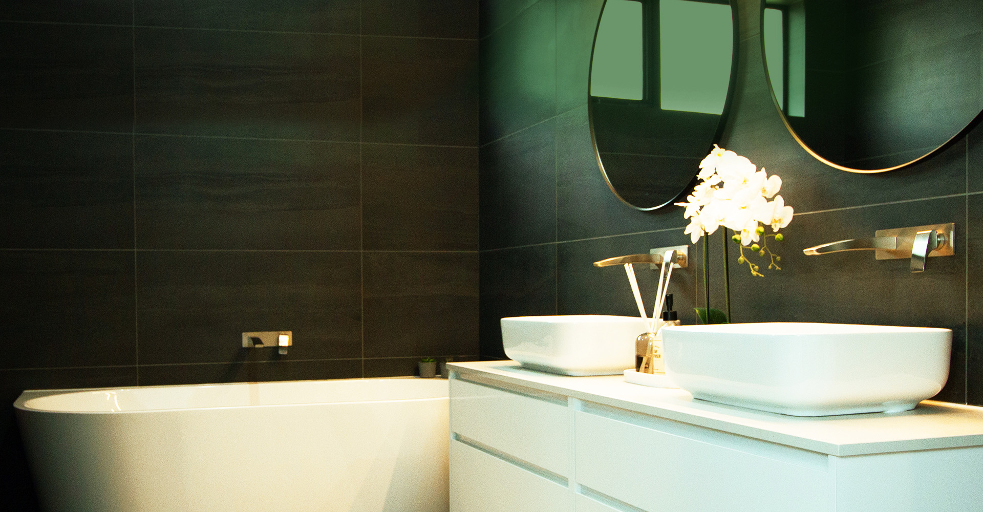 Modern bathroom with black wall tiles and white fixtures